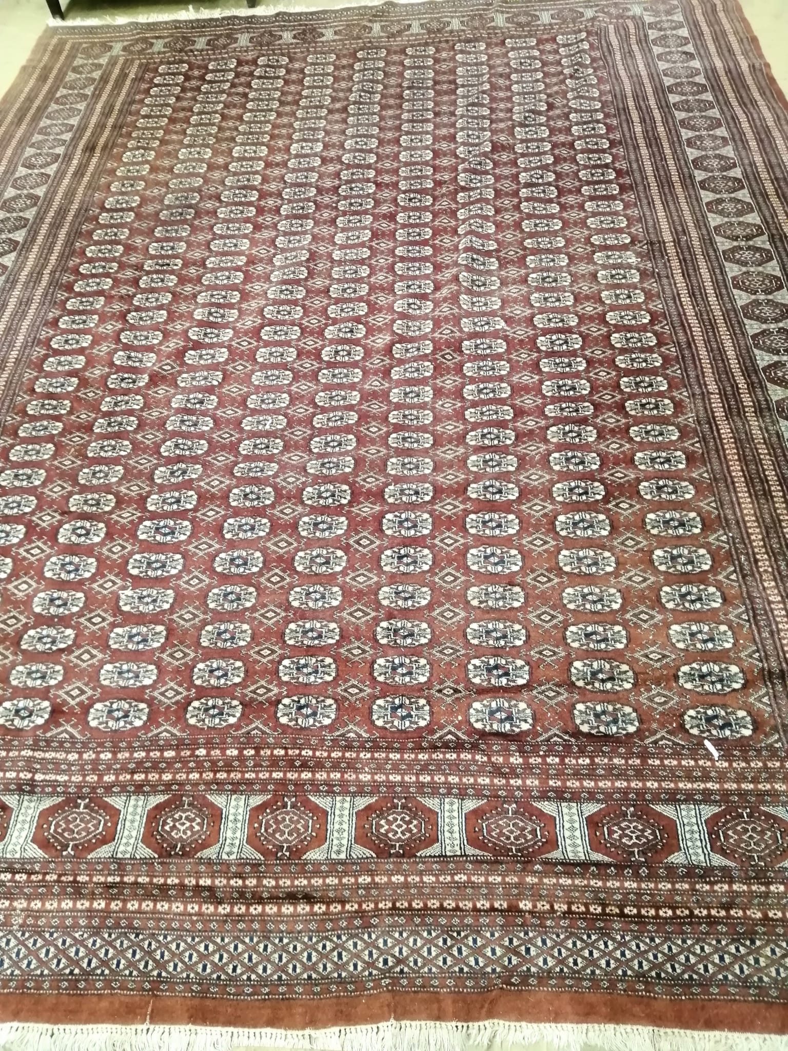 A Bokhara style burgundy ground carpet, 360 x 280cm